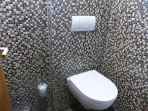 a bathroom with a white toilet in a tiled wall at Hotel Theile garni in Gummersbach