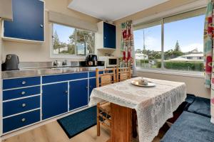 a kitchen with blue cabinets and a table at Sandy Cottage - Tokerau Beach Holiday Home in Kaitaia