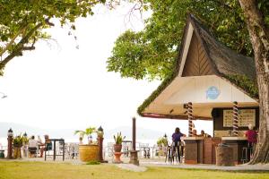 a restaurant under a tree with people sitting at tables at Holiday Villa Resort & Beachclub Langkawi in Pantai Cenang