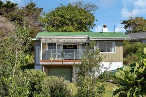 een huis met een groen dak en een balkon bij Sandy Cottage - Tokerau Beach Holiday Home in Kaitaia