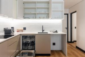 ケープタウンにあるSea Point - 17 Hall Rd,204 - Modern 1 Bedroom Apartment with Free Onsite Parkingの白いキャビネットと食器洗い機付きのキッチンが備わります。