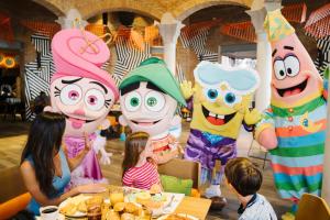 um grupo de crianças sentadas numa mesa em frente a personagens insufláveis em Nickelodeon Hotels & Resorts Punta Cana - Gourmet All Inclusive by Karisma em Punta Cana