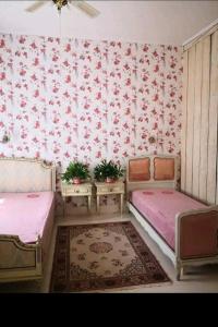 a room with two beds and floral wallpaper at Raudtee in Viljandi