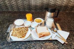 Goroomgo Hotel Happy Home Stay Khajuraho في خاجوراهو: صينية طعام مع الخبز والخبز المحمص على طاولة