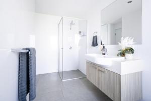 La salle de bains blanche est pourvue d'un lavabo et d'une douche. dans l'établissement Beautiful Modern 3 Bedroom Family Suite Sleeps 6, à Brisbane