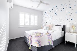 Beautiful Modern 3 Bedroom Family Suite Sleeps 6 في بريزبين: غرفة نوم بسرير وجدار به نقاط بولكا