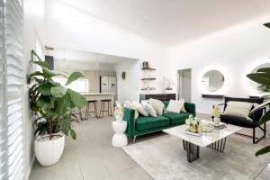Beautiful Modern 3 Bedroom Family Suite Sleeps 6 في بريزبين: غرفة معيشة مع أريكة خضراء وطاولة