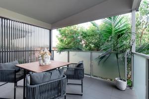 Beautiful Modern 3 Bedroom Family Suite Sleeps 6 في بريزبين: فناء في الهواء الطلق مع طاولة وكراسي خشبية