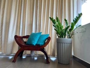 a chair with blue pillows next to a plant at Santa Maria, Trivandrum - An Airport Boutique by the Sea in Trivandrum