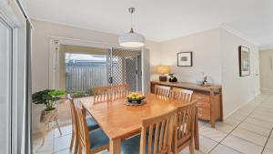 a kitchen and dining room with a wooden table and chairs at Aqua Links 70 The Drive Yamba in Yamba