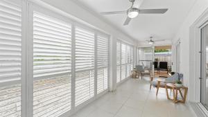 a living room with white plantation shutters on the windows at Aqua Links 70 The Drive Yamba in Yamba