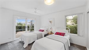 three beds in a white room with windows at Aqua Links 70 The Drive Yamba in Yamba