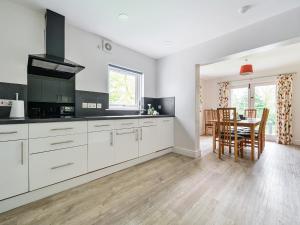 una cucina con armadi bianchi e tavolo con sedie di Elm - Woodland Cottages a Bowness-on-Windermere