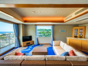ein Wohnzimmer mit einem Sofa und einem TV in der Unterkunft Ito Hotel Juraku in Ito