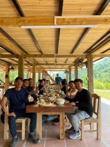 a group of people sitting around a wooden table at Tay Eco House in Nam Vong