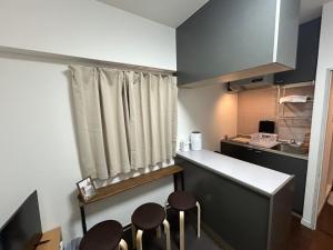 eine Küche mit einer Theke und einigen Hockern in der Unterkunft Guest House Raffine HAKATA in Fukuoka