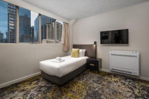 a hotel room with a bed and a flat screen tv at City Limits Hotel Apartments in Melbourne