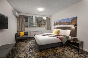 Habitación de hotel con cama y silla en City Limits Hotel Apartments, en Melbourne