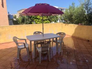 una mesa y sillas con una sombrilla en el patio en Le case di Bea, en Santa Teresa Gallura