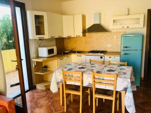 cocina con mesa con sillas y nevera azul en Le case di Bea en Santa Teresa Gallura