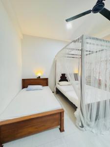 1 dormitorio con 1 cama y mosquitera en alovera inn, en Weligama