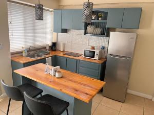 uma cozinha com armários azuis, uma mesa de madeira e um frigorífico em Apartamentos Carmela #2 em Siguatepeque