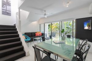 een eetkamer en een woonkamer met een glazen tafel en stoelen bij Unit 15 @ Tropical Reef: 2 mins to Four Mile Beach in Port Douglas