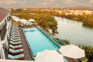 einen Blick über einen Pool mit Sonnenschirmen in der Unterkunft Little Oasis - An Eco Friendly Hotel & Spa in Hoi An