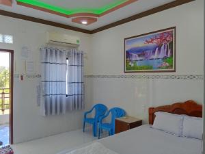 羅夷的住宿－Nhà Nghỉ Việt Thắng Dinh Thầy Thím，一间卧室配有一张床和两张蓝色椅子