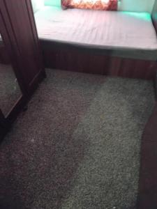 a bed in a room with a floor with carpet at Furnished Room in a house near train station,bus stop and town center in Plumstead