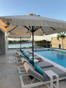 a row of lounge chairs and an umbrella next to a pool at Belmoral Corporate Suites in Townsville