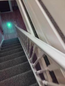 a flight of stairs in a building with a green light at Furnished Room in a house near train station,bus stop and town center in Plumstead