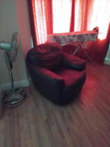 a living room with a red chair and a table at Furnished Room in a house near train station,bus stop and town center in Plumstead