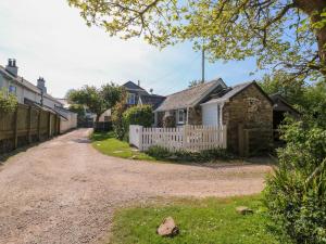 a house with a white fence and a gravel road at Toad Hall Cottage in Totnes