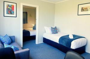 a bedroom with a bed and a chair and a mirror at Kurow Motel in Kurow