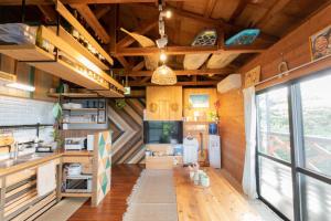 a kitchen with wooden walls and a large window at Mambo Hostel Okinawa in Motobu
