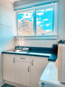 een keuken met een wastafel en een raam met een berg bij Kurow Motel in Kurow