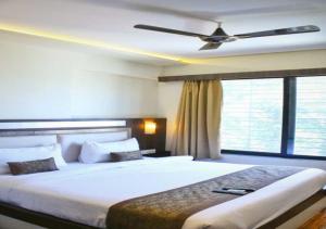 a bedroom with a large bed with a ceiling fan at Hotel Seven Sky in Nashik