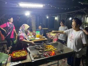 un grupo de personas de pie alrededor de una mesa con comida en LeThuHouse en Melaka