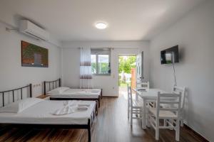Cette chambre comprend deux lits, une table et des chaises. dans l'établissement Eduard Lagji Apartament, à Lukovë