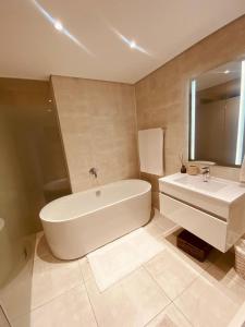 ein Badezimmer mit einer weißen Badewanne und einem Waschbecken in der Unterkunft Stunning 3Bed 2bath Oasis W King Bed in Midrand