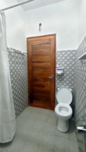 a bathroom with a toilet and a wooden door at Angin Mamiri Rinjani Cottages And Restaurant in Senaru
