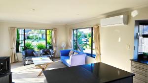 sala de estar con 2 sillas y sofá azul en Stunning Family Home en Auckland