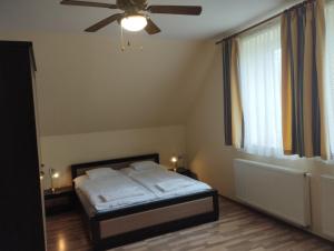 a bedroom with a bed and a ceiling fan at Tip-Top Lak Vendégház in Szilvásvárad