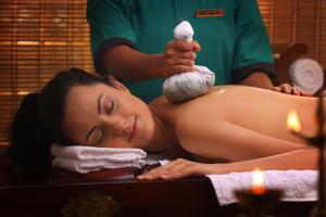 a woman getting a massage in a bath tub at Peter's Coffee Creek Wayanad Pool Resort and Spa in Wayanad +36 photos