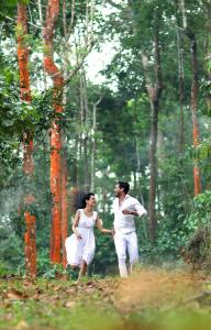 a man and a woman running through a forest at Peter's Coffee Creek Wayanad Pool Resort and Spa in Wayanad