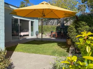 un gran paraguas amarillo en el patio de una casa en Studio Wing in Saint Heliers en Auckland