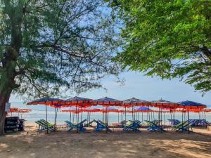 um grupo de cadeiras e guarda-sóis numa praia em Bann Pantai Resort em Cha Am