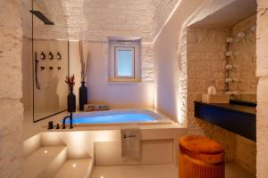 a bathroom with a tub with a window at Luxury Trullo Jacuzzi & Patio - Naiira in Alberobello +40 photos