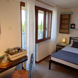 a bedroom with a bed and a desk and a window at da Dorian in Punat